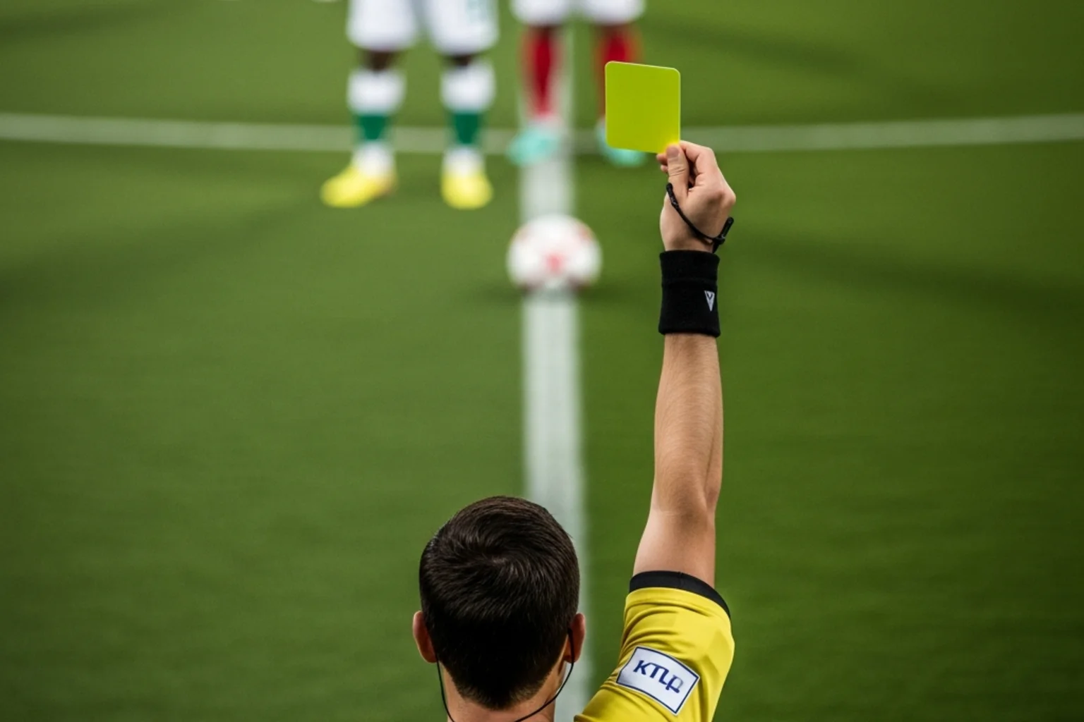 Árbitro de futebol a mostrar um cartão amarelo durante um jogo profissional
